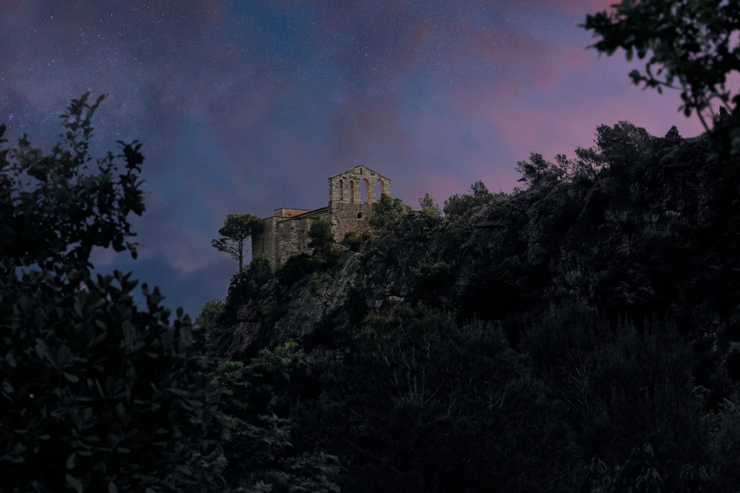 El Santuari de Foix recortado al atardecer, con la luna creciente sobre el cielo rosa y lila